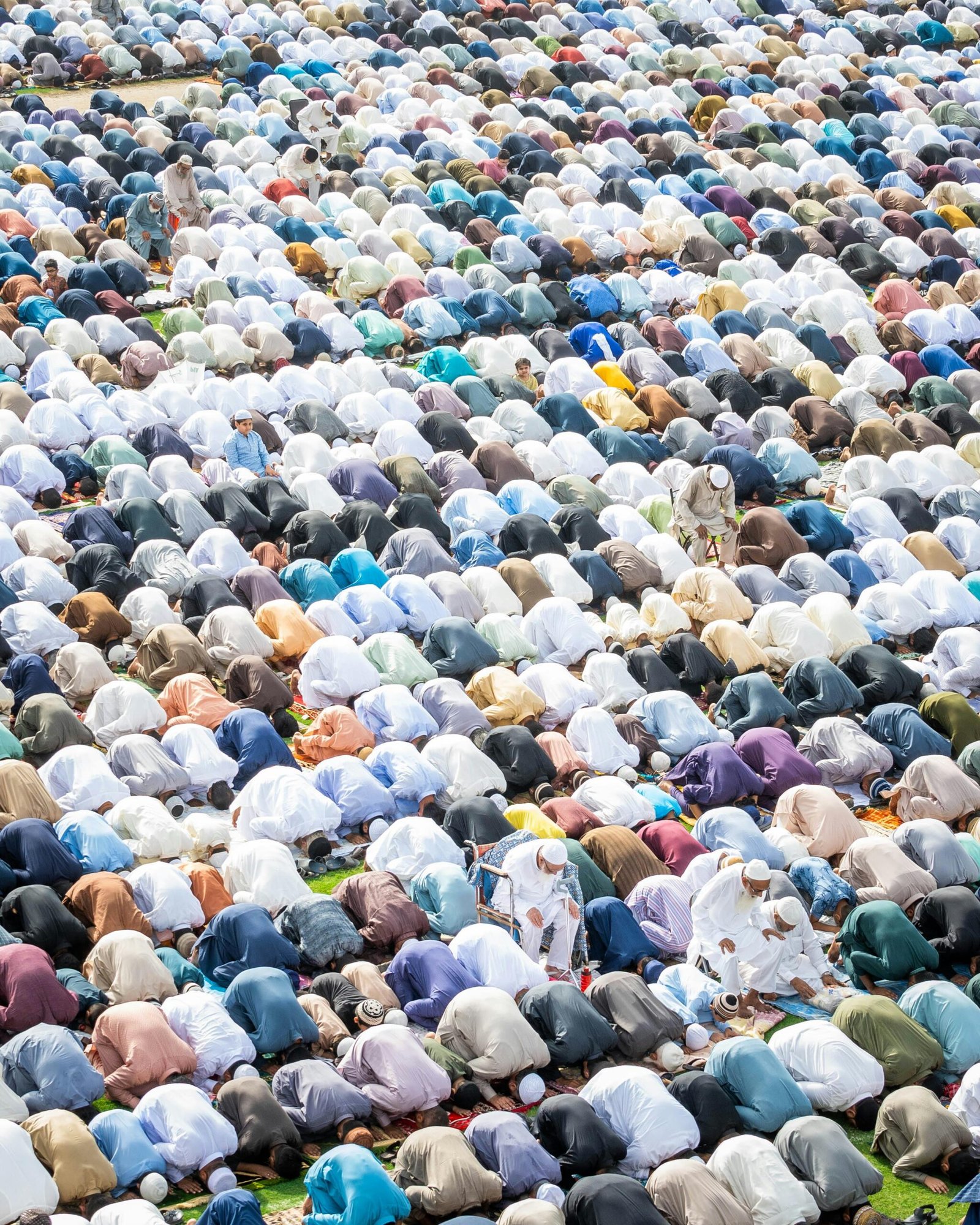 A high-angle view of a large group of Muslims praying outdoors, showcasing Islamic worship and unity.